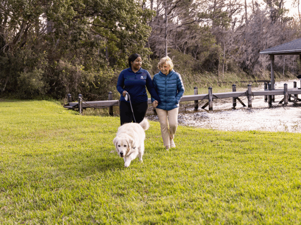Senior woman walking with caregiver and dog | Events for Seniors in Victoria: Fall & Winter 2025 on a Budget | Comfort Keepers Victoria | BLOG POST
